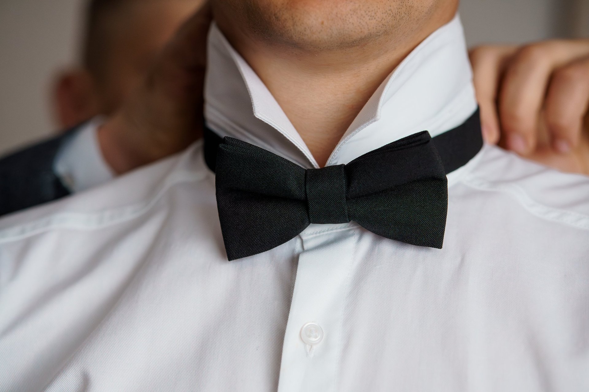 Groom adjusting bow tie before wedding
